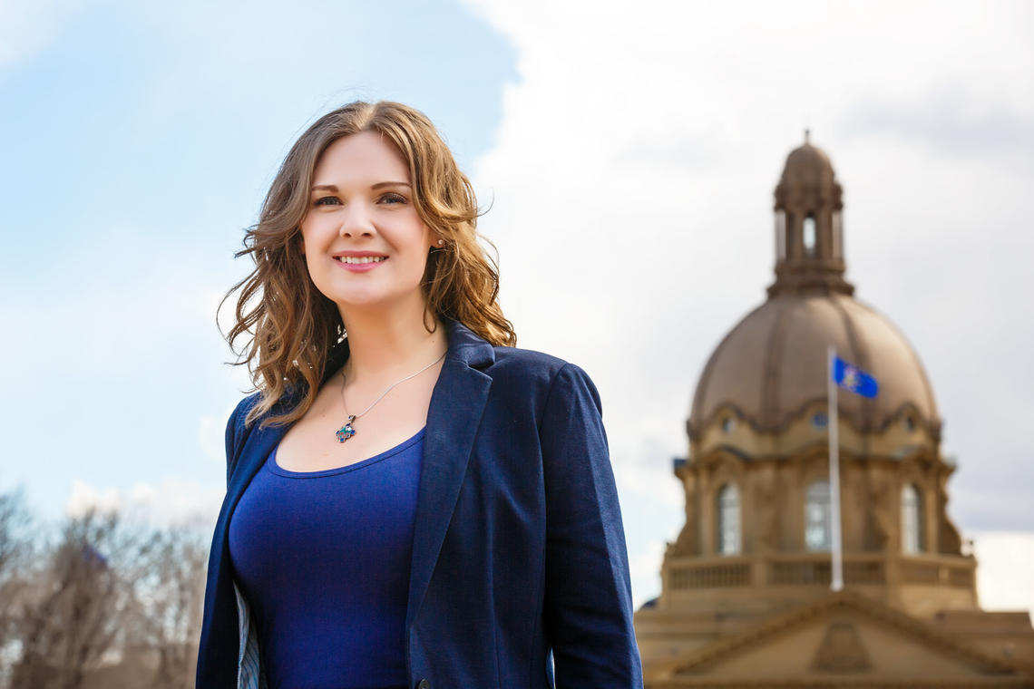 Alumna Jennifer Burgess stands in front of the Alberta legislature building