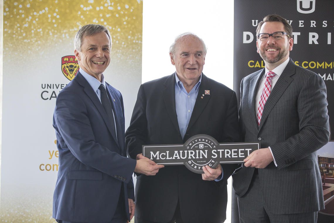 Current Chancellor Robert Thirsk, left, and James Robertson, president and CEO of West Campus Development Trust, present a street sign to his Honour Doug Mitchell on behalf of C. Campbell McLaurin, the university's first chancellor (1966 – 1970). 