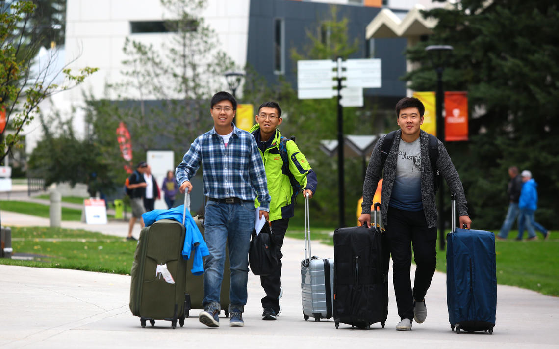 Students with suitcases come to campus