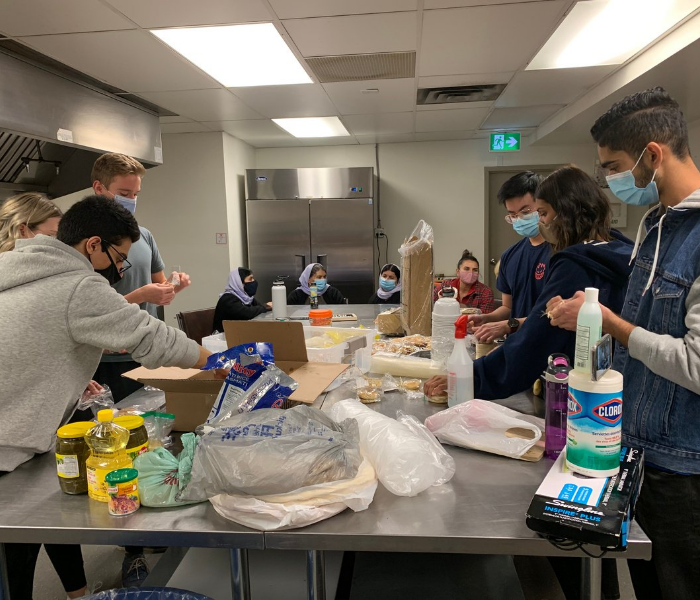 Nursing students and the Yazidi work to prepare and assemble goods for sale at the Bowness Community Centre.