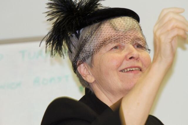 woman in a feathered hat, raising her arm