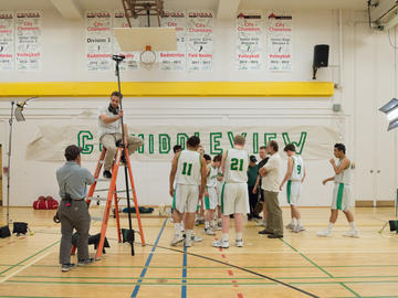 A basketball team and a film crew in a gymnasium