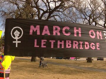 DeLucia-Burk holding a banner at a women's day demonstration.