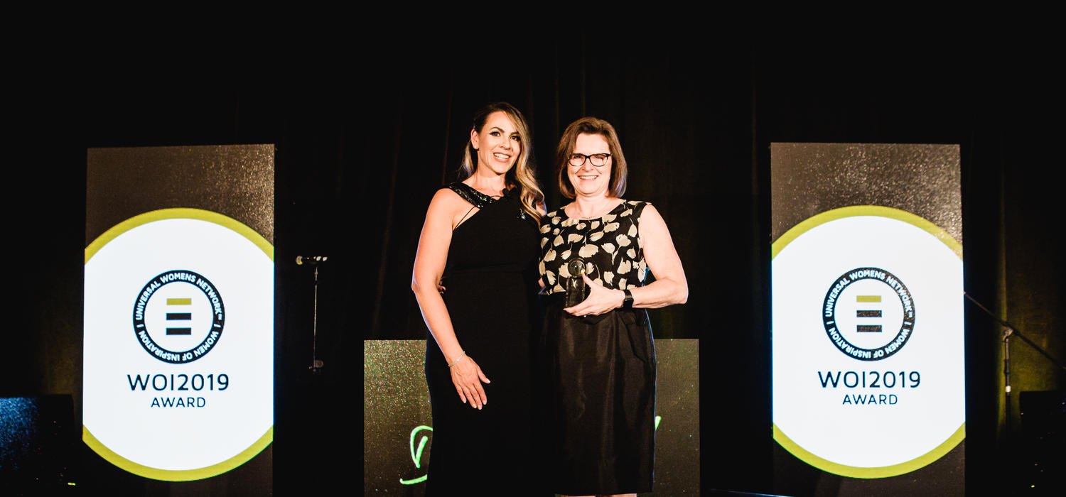 Dr. Lesley Rigg receives a Women of Inspiration Western Canada Award. She is pictured on stage with awards founder Monica Krestchmer.