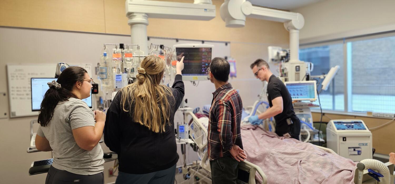 A team of people stand around a hospital bed